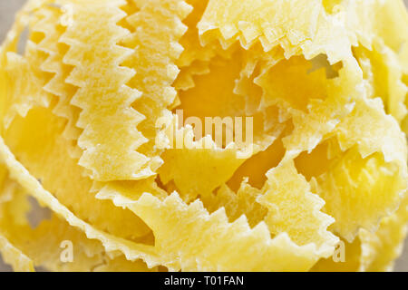 Bellissimo il nido di fettuccine close up , nastri sottili di pasta con bordi geometrica e superficie ruvida Foto Stock