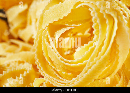 Bellissimo il nido di fettuccine close up , nastri sottili di pasta con bordi geometrica e superficie ruvida Foto Stock