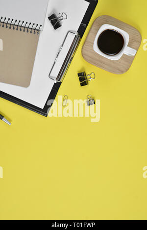 Mock up area di lavoro vuoto con clip board, forniture per ufficio, penna, tazza di caffè e occhiali su sfondo giallo. Piatto, laici vista superiore Foto Stock