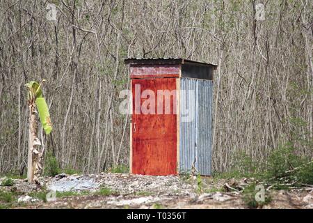 Una dipendenza di un tetto dello stagno con dipinto di rosso la porta spazzola scrub Foto Stock