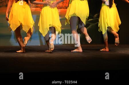 I giovani ballerini in abiti di colore giallo ballando sul palco Foto Stock