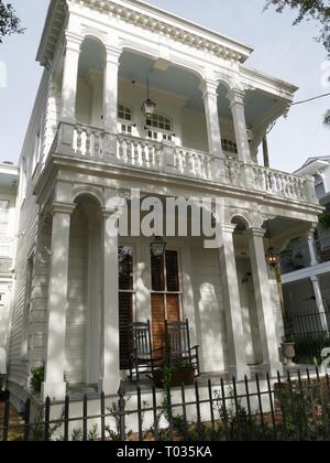 Una bella casa coloniale bianca con sedie a dondolo nel balcone lungo la storica Charles Avenue a New Orleans, Louisiana. Foto Stock