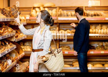 L uomo e la donna la scelta di pasticceria fresca nel reparto panetteria del supermercato Foto Stock