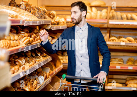 Imprenditore bello la scelta di pasticceria fresca nel reparto panetteria del supermercato Foto Stock