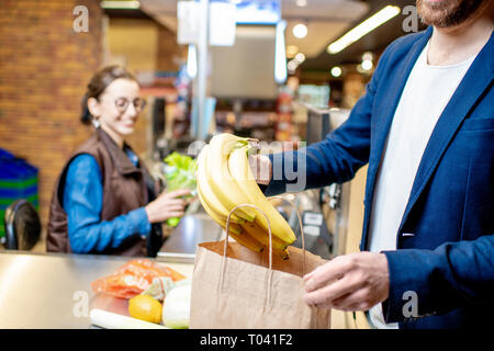 Imprenditore acquisto di cibo sano e di imballaggio dei prodotti destinati alla cassa con cassa sullo sfondo, vista da vicino Foto Stock