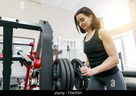 Giovane bella donna atletica brunette facendo esercizi di fitness in palestra. Fitness, sport, formazione, persone, uno stile di vita sano concetto Foto Stock