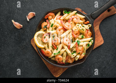 Penne Pasta con scampi o gamberetti su nero, vista dall'alto, copia dello spazio. Pasta di limone con gamberi saltati, piatti a base di frutti di mare freschi. Foto Stock