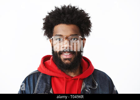 Colpo di testa di un ambizioso e bello giovane creative african american freelancer con naso forato e acconciatura afro in bicchieri sorridente con gioia a Foto Stock