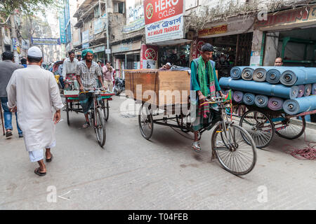 Uomo di trasporto di merci su un risciò ciclo attraverso la città di Dacca in Bangladesh. Foto Stock