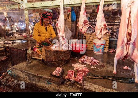 Coloratissimo mercato di carne con i fornitori commerciali e persone che trasportano merci nelle strade di Dacca in Bangladesh Foto Stock