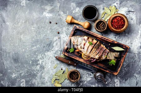 Grigliate di pesce intero caricato con gli agrumi, le erbe aromatiche e le spezie in cucina rustica board Foto Stock