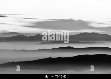 La nebbia di riempimento di una valle in Umbria (Italia), con strati di montagne e colline Foto Stock