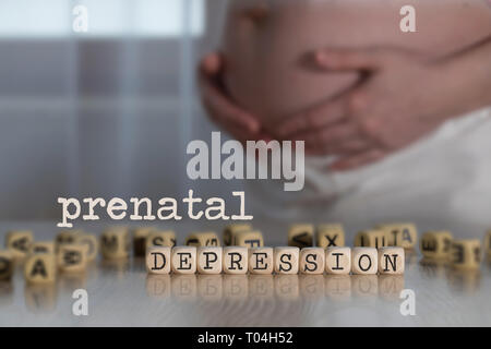 Parole depressione prenatale composto da lettere di legno. Donna incinta in background Foto Stock