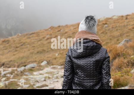 Donna che indossa una sciarpa e cappello invernale vista posteriore esterno Foto Stock