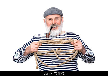 Foto ritratto di un allegro marinaio con il suo tubo e barba grigia, tenendo una corda Foto Stock