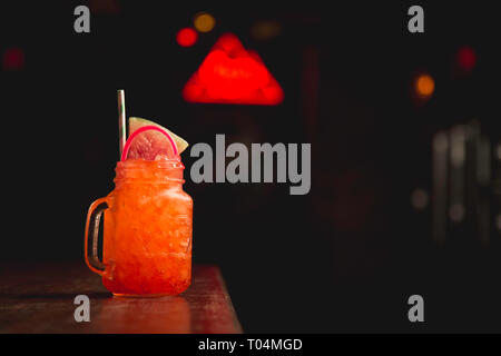 Bizzarre glow stick cocktail sul bar con neon sign in background Foto Stock