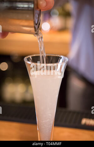 Versando frizzanti cocktail in a tall class close up Foto Stock