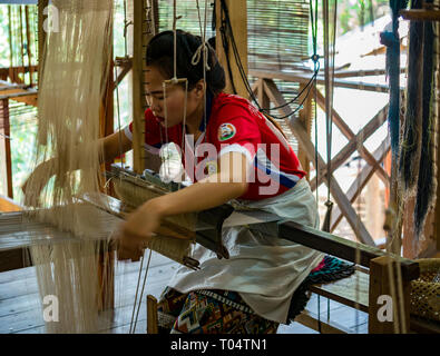 Lavoratore di sesso femminile che tessile di tessitura a telaio a cooperative di officina, Luang Prabang, Laos, Asia Foto Stock