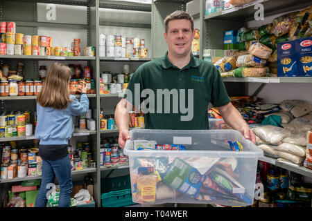 Dei volontari in un Regno Unito Trussell fiducia chiesa locale food bank ripiani di imballaggio e tenendo le donazioni Foto Stock