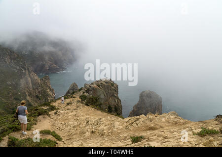 CABO DA ROCA, Portogallo - 2 Settembre 2018: turisti su Capo Roca scogliere nella nebbia. Le rocce sono oscurata da nuvole o nebbia. Capo Roca è più a ovest par Foto Stock