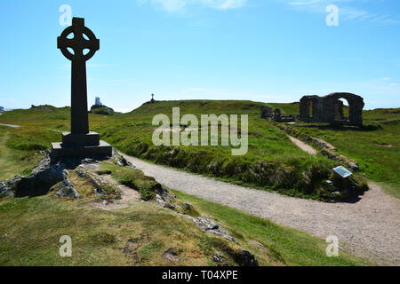 La croce, chiesa e faro sull isola di Llanddwyn che è al largo della costa di Anglesey nel Galles del Nord Foto Stock