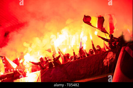 I teppisti con maschera di torce di contenimento nel fuoco mentre a sostenere la loro squadra durante una partita a Stadium Foto Stock
