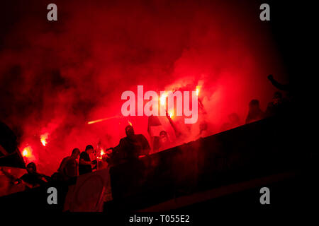 I teppisti con maschera di torce di contenimento nel fuoco mentre a sostenere la loro squadra durante una partita a Stadium Foto Stock