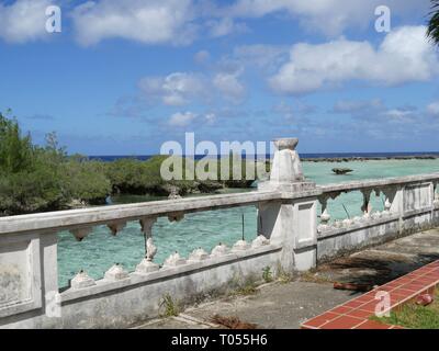 Le acque blu del mare con isole verdi visto dal parco acquatico abbandonati con rotture di ringhiere su Rota, Isole Marianne del Nord Foto Stock