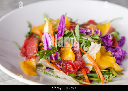 Closeup fresca insalata estiva con bresaola carne, verdi, rucola, mango, la carota e il cavolo cinese. Concetto delicatezza italiano, il nuovo menu in un quartiere alla moda di restaur Foto Stock