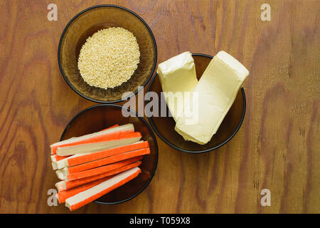 Parte degli ingredienti per la preparazione di sushi in lastre sulla tabella, ossia il riso, formaggio fuso, i cetrioli e i bastoncini di granchio 2019 Foto Stock