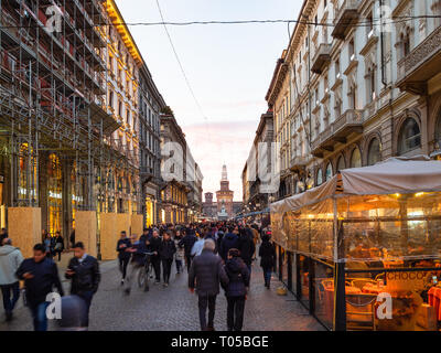 Milano, Italia - 24 febbraio 2019: la gente sulla strada Via Dante e la vista del Castello Sforzesco di Milano in serata. Milano è la capitale di L Foto Stock