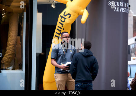 Un dipendente si impegna con un membro del pubblico sul marciapiede fuori da un negozio Sprint nel centro di Philadelphia, PA il 15 marzo 2019. Foto Stock