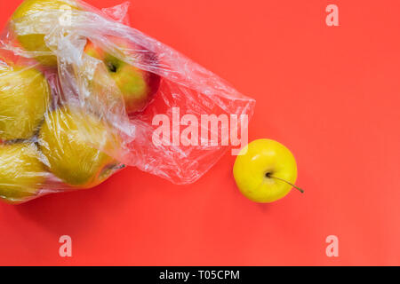 Una mela gialla laminati fuori del sacchetto di plastica con le mele su sfondo orale. Foto Stock