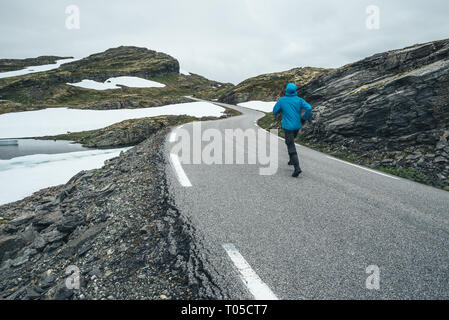 Norwegian itinerario panoramico Aurlandsfjellet. Un ragazzo in una giacca blu che cammina per le strade di montagna Bjorgavegen in Norvegia Foto Stock