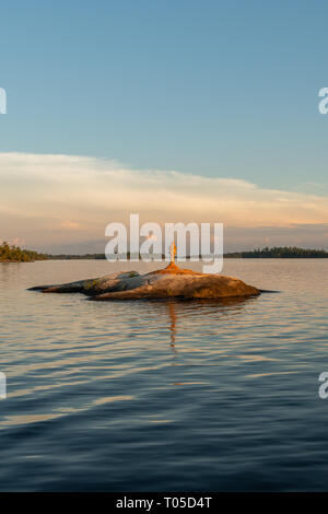 Cairn sulla piccola isola di roccia nel lago di pioggia a fine Afternooon Foto Stock