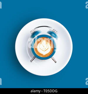 Orologio sveglia con il quadrante di cappuccino su sfondo blu. In stile minimale di caffè il concetto di tempo. Foto Stock