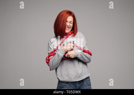 Ragazza impigliate in una catena,un i capelli rossi donna con capelli castani cerca di sbarazzarsi della catena Foto Stock