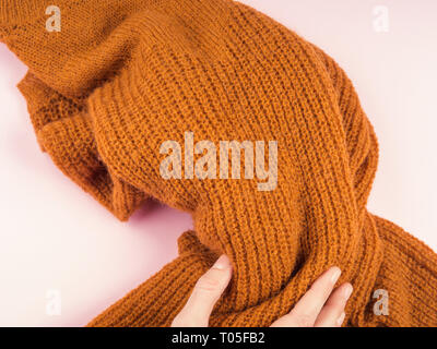 Accogliente maglione giallo in rosa con la donna la mano tenendolo Foto Stock