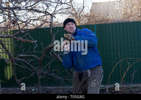 Uomo in abiti da lavoro lavora in giardino Foto Stock