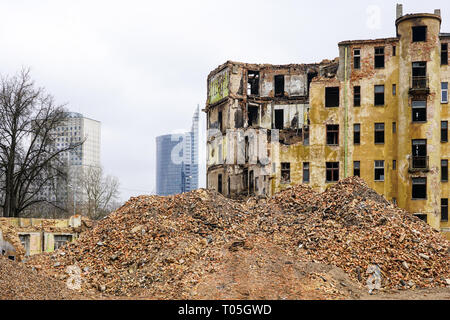 Demolizione di un grande storico di vecchia casa di pietra nella città, nuovi edifici a più piani in background, la pila di mattone in primo piano Foto Stock