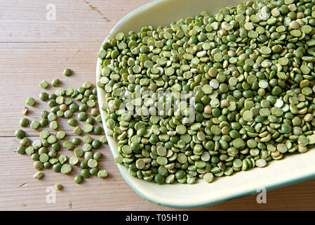 Piselli verdi spaccati su un piatto vintage in smalto verde sul tavolo della cucina Foto Stock