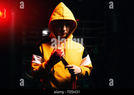 Sport boxer donna in felpa gialla tira bende rosse sulle mani. Foto Stock