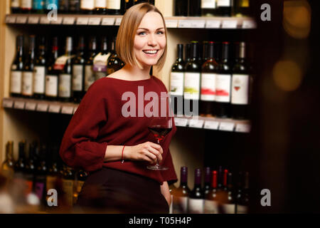 Immagine della ragazza con un bicchiere in mano in negozio con il vino Foto Stock