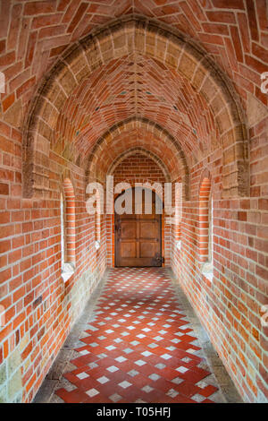 Antiche in legno porta alla fine del corridoio di mattoni Foto Stock