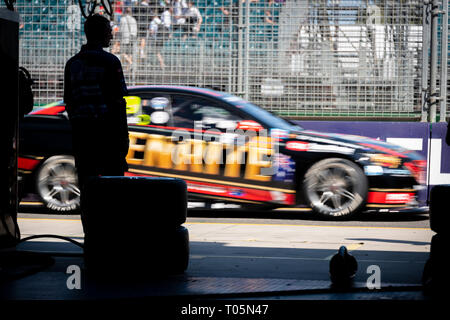 Un membro di un equipaggio buca, in silhouette, guardando cars andare attraverso la pit lane durante un V8 Supercar gara Foto Stock