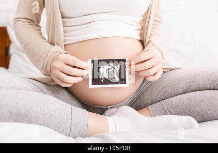 Donna incinta azienda foto di ultrasuoni vicino al ventre Foto Stock