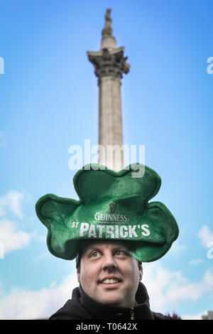 Londra, UK, 17 Mar 2019. Un uomo in shamrock hat davanti alla statua di Nelson, Trafalgar Square. Londra celebra con una spettacolare il giorno di San Patrizio parade. Credito: Imageplotter/Alamy Live News Foto Stock