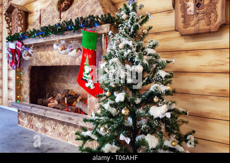 Camino con albero di Natale e regalo rossa calza vicino a parete in legno Foto Stock