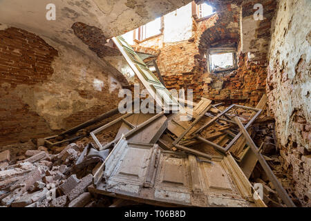 Vecchio abbandonato vuoto sala nel seminterrato del palazzo antico o palazzo con incrinato intonacate pareti in mattoni con soffitto basso, piccole finestre con e spazzatura su sterrato Foto Stock