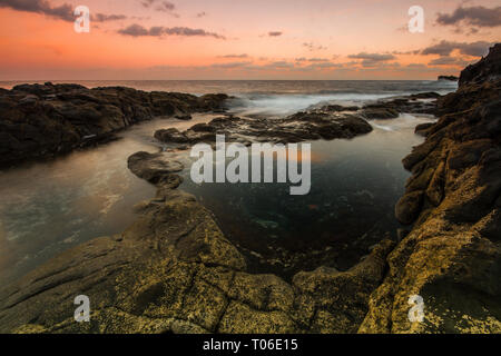 Una lunga esposizione sunrise e colorati di cielo, roccia vulcanica bellissimo paesaggio marino a Gran Canaria Island Costa in Spagna. Foto Stock